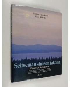 Kirjailijan Veikko Huovinen käytetty kirja Seitsemän sinisen takana : kuvakirja Sotkamosta = Bortom sju blånande berg : bilder från Sotkamo = Behind seven blue-tinged hills : Sotkamo in pictures = Und blau schimmern die Berge : Bilder aus Sotkamo